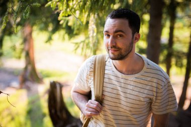 Ormanda yürüyüş sırt çantası ile mutlu sakallı adam gezgin. Turizm, seyahat, Macera, kavram - gülümseyen genç adam ormanda sırt çantası ile yürüme yürüyüş. Temiz hava ve sağlıklı yaşam kavramı.