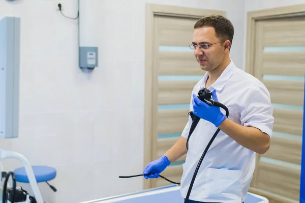 Proctólogo sosteniendo un anoscopio contra una silla proctológica. En el hospital. — Foto de Stock