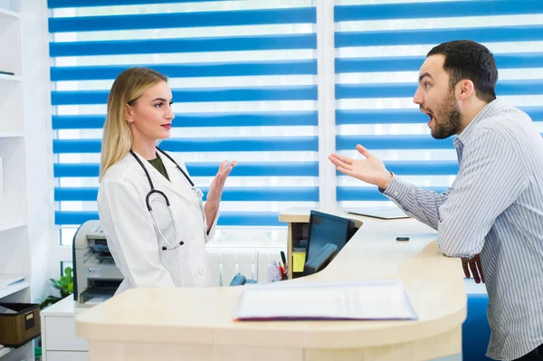 Uomo che parla con la receptionist donna in ospedale — Foto Stock