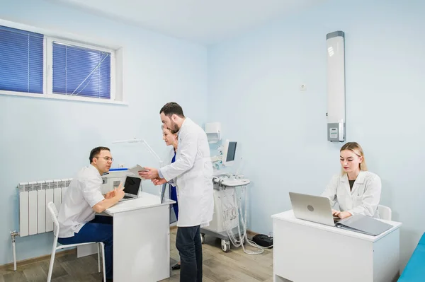 Groupe de médecins impliqués dans une discussion sérieuse avec les dossiers médicaux — Photo