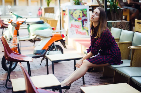 Vue ci-dessus jolie femme en robe à carreaux violette assise à table sur la terrasse de la cafétéria. Elle regarde vers la caméra — Photo