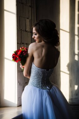 Dikiz pencerenin yakınındaki gelin silueti kırmızı çiçekler kokuyor