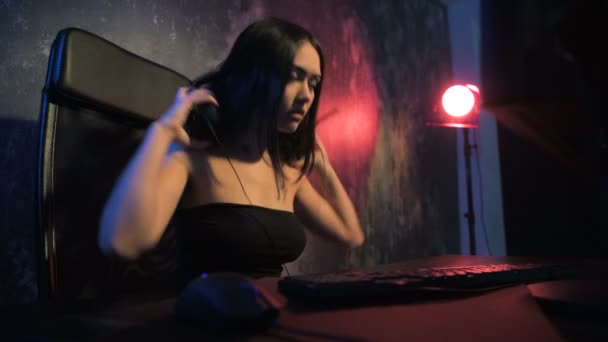 Mujer comienza juego en línea con sus freinds. Gamer chica jugando juego en línea en una computadora PC con auriculares y hablando con un equipo usando micrófono — Vídeos de Stock