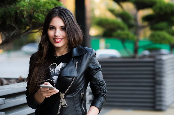 Mujer caminando y usando un teléfono inteligente en la calle durante el soleado día de verano — Foto de Stock