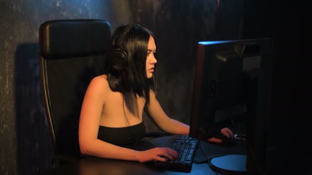Mujer seria gamer jugando juego en línea en una computadora PC con auriculares y hablando con un equipo usando micrófono — Vídeos de Stock