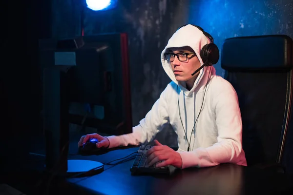 male hooded gamer playing online game on pc computer