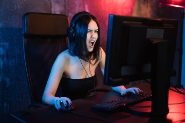 Teknolojisi, oyun, eğlence, sağlar oyun ve insanlar kavramı - kızgın çığlık atan genç kız evde oyun oynarken ve playthrough veya anlatım video akarsu Pc bilgisayar ile kulaklık.