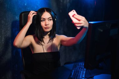 En iyi görünüm güzel kızın evde rahatlatıcı bir smartphone kullanarak ve siyah kulaklık giyen müzik oynuyor.