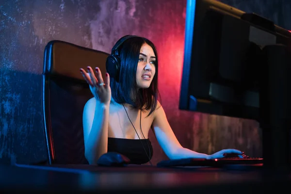 お使いのコンピューターに恐怖のゲーマー演劇ゲーム。ヘッドフォンで感情的な若い女性は、コンピューター上のゲームを果たしています。ゲーマーのコンセプト. — ストック写真