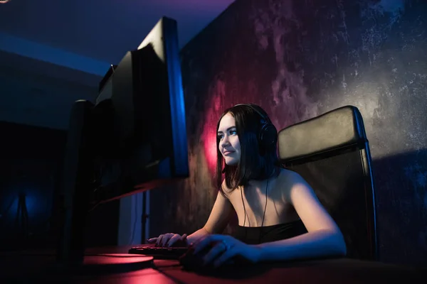 Fille concernée gamer dans les écouteurs jouer à des jeux de réseau se préparant à participer à des compétitions internationales dans e-sports . — Photo