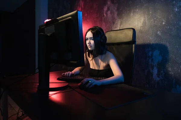 Mujer atractiva joven jugando videojuegos en su computadora con auriculares para juegos . —  Fotos de Stock