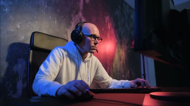 Glücklich lächelnder junger Mann in Headset mit PC-Computerspiel zu Hause und Streaming-Playthrough oder Durchlaufvideo und Gespräch über Mikrofon. Technologie, Gaming, Unterhaltung, lässt spielen und — Stockvideo