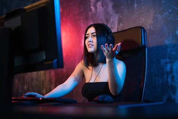 Verängstigte Gamer spielen Spiele auf Ihrem Computer. eine emotionale junge Frau mit Kopfhörer spielt Spiele am Computer. Spielkonzept. — Stockfoto