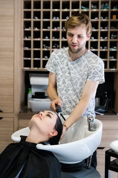 Uomo parrucchiere lavaggio testa cliente. Un padrone di capelli dell'uomo che innaffia i capelli delle ragazze con una doccia in uno studio di capelli . — Foto Stock