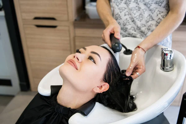 Menina bonita desfrutando de lavagem de cabelo no salão de cabeleireiro . — Fotografia de Stock