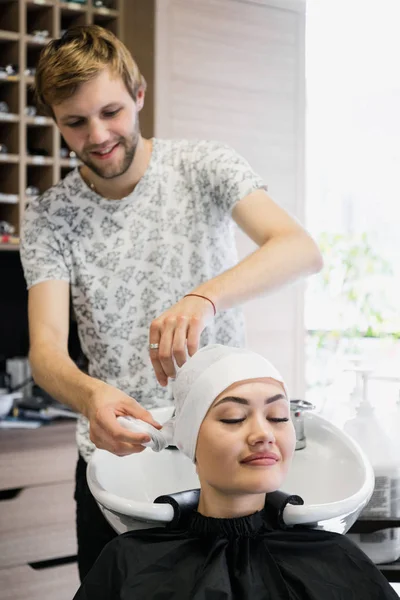 Bájos fiatal nő boldogan mosolyogva, miközben készül a haját a hajvágás, szárítás egy törülközővel professzionális férfi fodrász — Stock Fotó