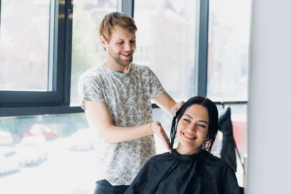 Mužské kadeřnice, usmíval se a mluví se zákazníkem přitom nový účes krásná mladá bruneta žena — Stock fotografie