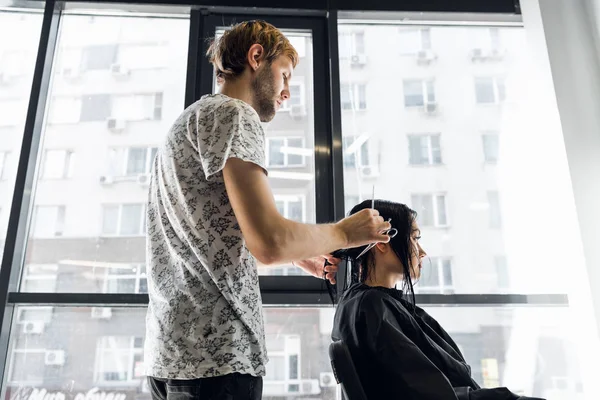 A woman in a hairdressing salon waiting to see the results looking in a mirror, smiling and talking with artist — Stock Photo, Image
