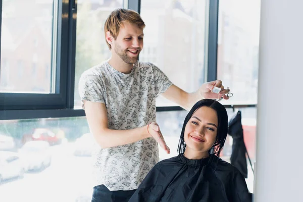 Jeune femme regardant dans le miroir après la coupe de cheveux . — Photo