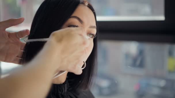 Friseur schneidet Haare einer schönen ernsten brünetten Frau — Stockvideo