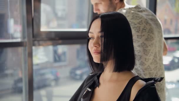 Coiffeur avec peigne et ciseaux coupe les cheveux de la cliente. Femme dans salon de beauté coiffure . — Video