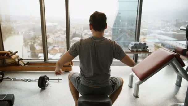 Sportieve man die zich uitstrekt armen voor training van de gymnastiek. Fitness jonge mannelijke atleet permanent binnen in de fitnessruimte van het hotel met geweldig uitzicht warming-up. — Stockvideo