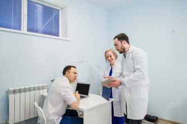 Sağlık personeli dizüstü ve tablet pc kullanarak tıbbi raporlar üzerinde tartışıyor. Sağlık çalışanlarına hastane ofiste tartışma.