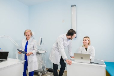 Üç doktor ofisinde bir toplantı görürken tedavisinin yeni yol tartışırken birlikte fotoğraf. Yeni yol tedavi tartışırken dizüstü bilgisayar kullanan doktorlar.