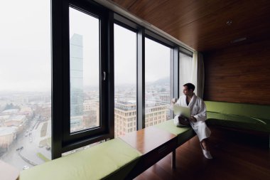 Kahve içme ve dizüstü bilgisayar sabahleyin yatakta kullanarak mutlu adam