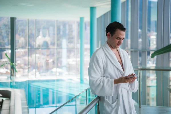 Hombre usando teléfono celular cerca de la piscina cubierta —  Fotos de Stock