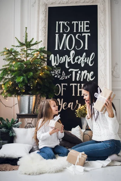 Feliz Natal e Boas Festas. Mãe alegre e sua linda filha menina trocando presentes. Pais e criança se divertindo perto da árvore de Natal dentro de casa. Família amorosa com presentes no quarto . — Fotografia de Stock