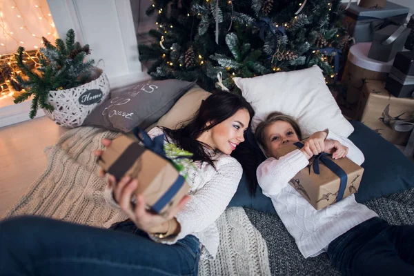 Mutter und Tochter liegen mit Geschenken unter dem Weihnachtsbaum, Draufsicht — Stockfoto