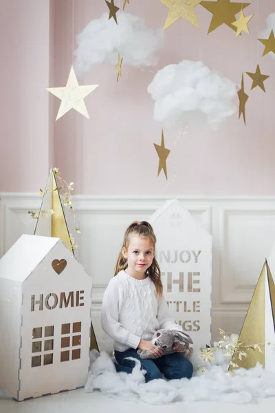 Schattig klein meisje zitten in decoratie met kleine huisjes en wolken — Stockfoto