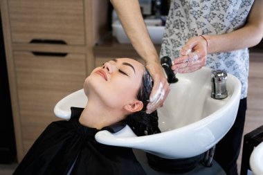 Kuaför Salonu. Güzel esmer kadın saç yıkama sırasında