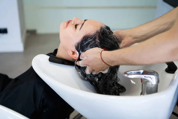 Linda morena lava o cabelo em um salão de beleza — Fotografia de Stock