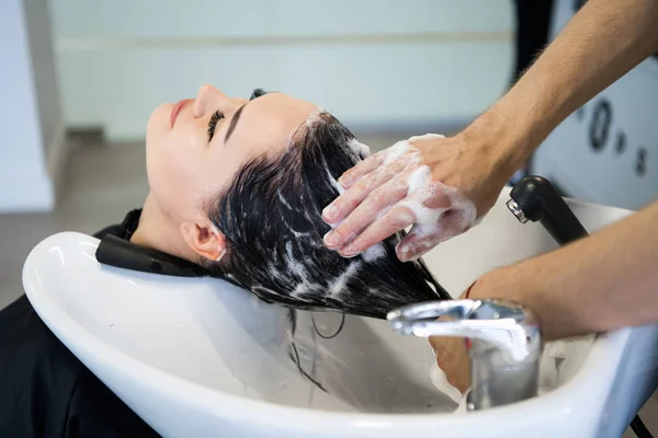 Parrucchiere professionista irriconoscibile che lava i capelli al suo cliente. Bella parrucchiere lavare i capelli alla sua signora cliente in parrucchiere. Cliente seduta con gli occhi chiusi . — Foto Stock