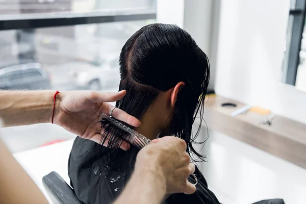 Tangan Mans dipotong dan menyisir perempuan berambut cokelat gelap di salon kecantikan dengan cermin — Stok Foto