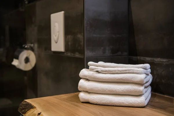 Bathroom still-life, white towels on wooden table and toilet paper — Stock Photo, Image