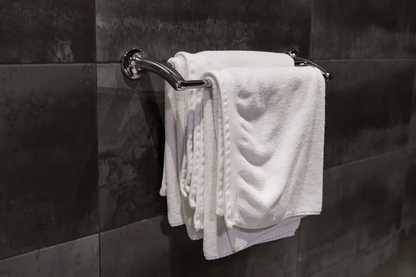 Clean white towels on a hanger at bathroom against grey wall tiles — Stock Photo, Image