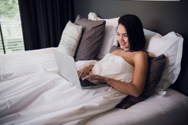 yatak üstünde laptop ile güzel bir genç kadın portresi