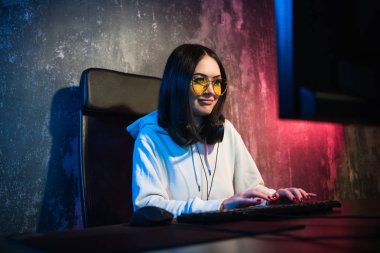 Güzel dost Pro Gamer kız yapar Video oyunu oyun akışı, giyen kulaklık görüşmeler ve kulaklık mikrofon içine onun hayranları ve takım ile sohbetler. Gençler eğleniyor. Arka plan Neon Retro renkleri