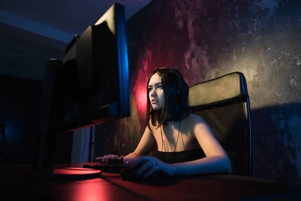 Κατακόρυφος βολή της ένα χαμογελαστό όμορφο κορίτσι Gamer επαγγελματική παίζοντας σε First-Person Shooter παιχνίδι Online βίντεο στον προσωπικό υπολογιστή της. Casual χαριτωμένο Geek μιλούν στα ακουστικά — Φωτογραφία Αρχείου