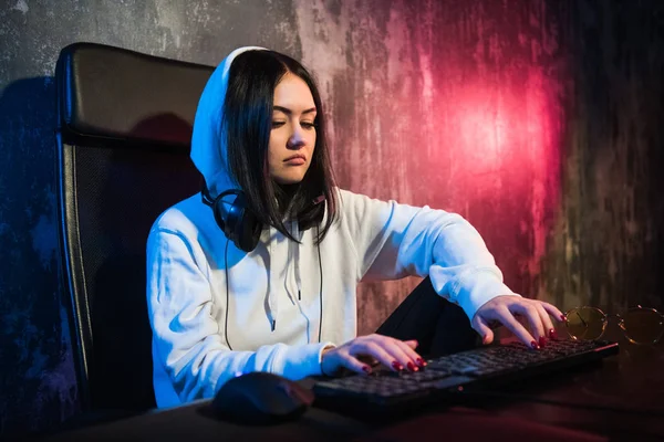 Retrato de la hermosa chica gamer profesional jugando en el videojuego en línea, geek lindo casual con gafas, charlas y charlas con sus compañeros de equipo y amigos a través de auriculares. neón de color —  Fotos de Stock