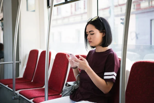 Retrato al aire libre de una joven hermosa mujer usando su teléfono móvil en un autobús . — Foto de Stock