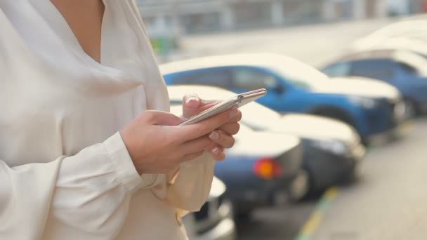 Acercamiento de una mano de mujer joven mientras usa su teléfono inteligente al aire libre en una ciudad. Movimiento lento — Vídeos de Stock