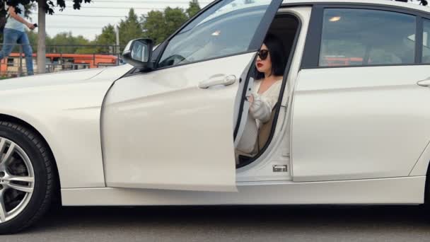 Элегантная брюнетка-деловая женщина-водитель в белой юбке и блузке выходит из машины в замедленной съемке . — стоковое видео