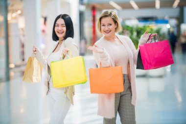 Alışveriş torbaları alışveriş merkezinde yürüyen iki mutlu arkadaşlar kızlarla