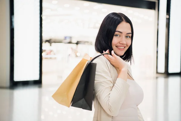Женщина в магазине. Счастливая женщина с сумками, наслаждающаяся покупками. Концепция потребительства, шопинга, образа жизни. — стоковое фото