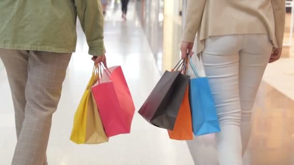 Benen van shopaholics met tassen van de shopping mall lopen. Slow-motion. Vrouwelijke vrouwen lopen bij winkelcentrum. — Stockvideo