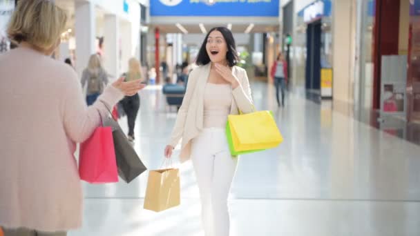 Две счастливые девушки встречаются с объятиями в универмаге во время шоппинга . — стоковое видео